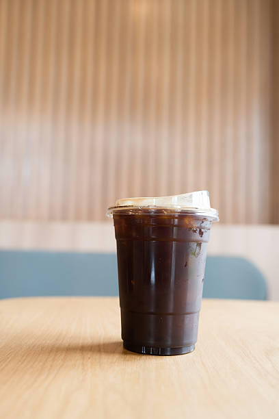 Iced americano coffee in disposable glass on wood table