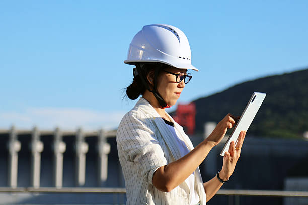istock Asian female engineer using mobile phone and tablet to work on site 2237874668