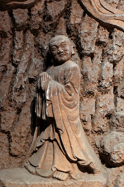 Buddhist stone statue in the Ten Thousand Buddha Cave at the Oriental Buddha Capital (Dongfang Fodu) in Leshan, China, known for its intricate rock carvings of numerous Buddha statues, bodhisattvas, and arhats. It is considered the fifth-largest Grotto group in China and a significant attraction alongside the famous Leshan Giant Buddha.