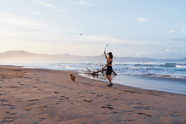 istock Woman walking on the beach while playing with her pets 2237874786