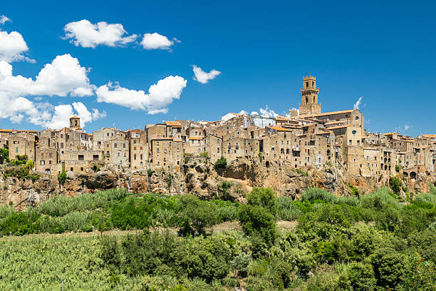 Pitigliano, a historic cliffside town, featuring medieval architecture under a blue sky in Tuscany