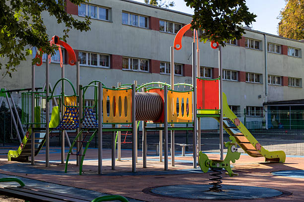 istock Colorful empty playground with modern equipment like a slide, tunnel, and climbing structure, designed for children's recreation and outdoor fun near a school building 2237882941