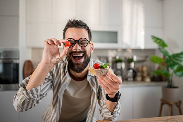 istock Happy man having fun with cherry tomato preparing snack 2237890624