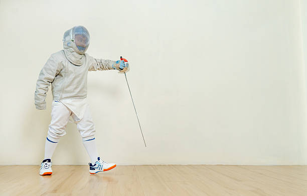 Asian boy with fencing sport uniform hold epee as protect action during practice for the competion.