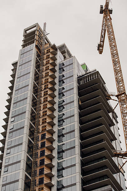 istock Modern High-Rise Under Construction With Crane Tower And Glass Facade In Urban Development Site 2237894343