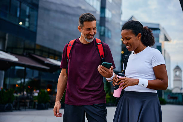 istock Happy couple walking downtown using smartphone 2237894470