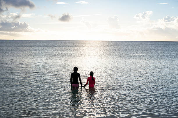 istock Sisters stand in sea together at sunset 2237902431