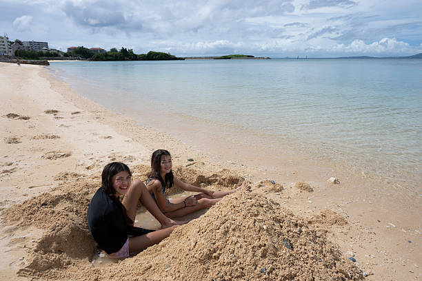 Young girls play on sandy beach, Onna, Okinawa