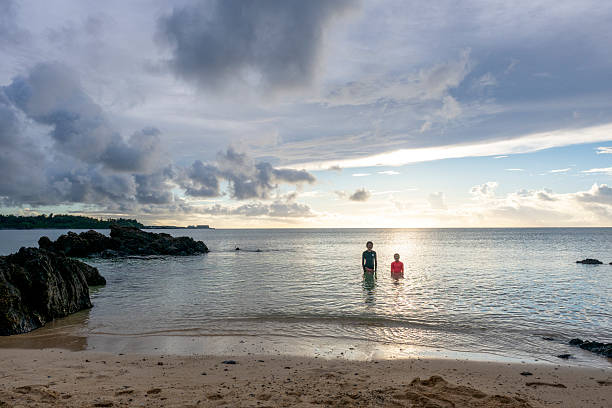 Elevated view of young girls exploring sea shallows at sunset, Onna , Okinawa