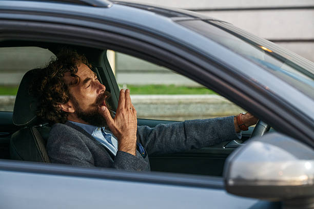 istock Tired businessman yawning while driving car 2237909265