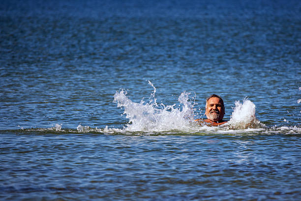 Friendly middle-aged man splashing in the Baltic Sea in summer.