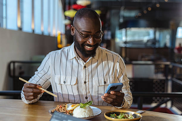 istock Man enjoying lunch at a casual restaurant while using his smartphone during a work break 2237919594