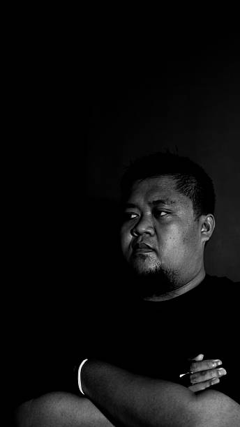 istock Asian man facing back with arms folded across chest, black and white concept, dark backdrop enhancing bold and confident stance. 2237931708