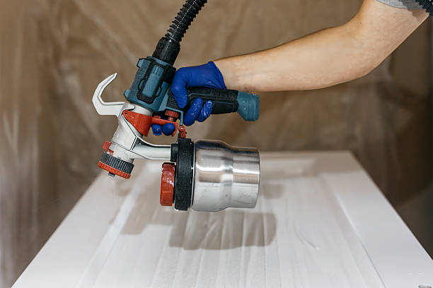 istock Skilled individual using a paint sprayer with a metallic container, applying paint to a smooth surface 2237933606
