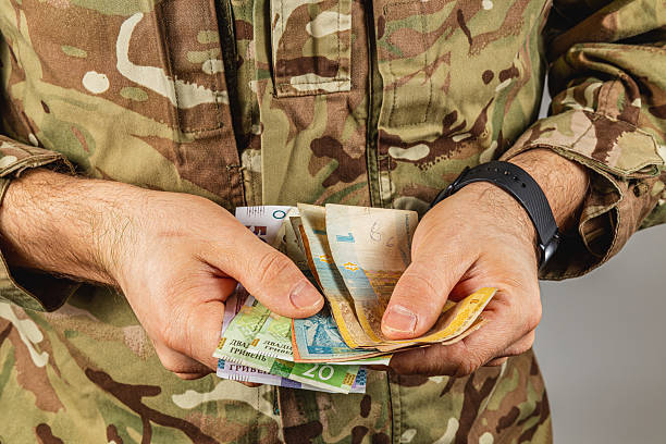 istock Soldier counting money indoors in camouflage uniform 2237938526