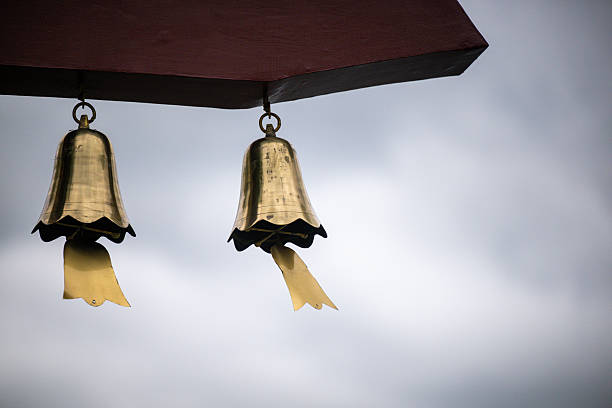 Ancient Bronze Bells Hanging Under a Wooden Structure Against a Cloudy Sky