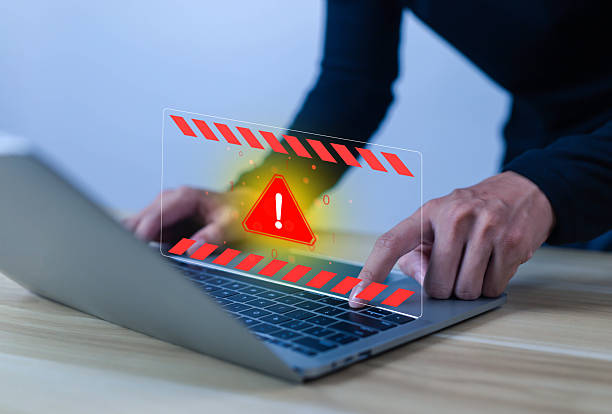istock Cybersecurity warning concept showing a red alert symbol on laptop screen, representing virus attack, malware, system error, online data breach, and computer security risk. 2237966808