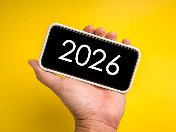 istock Creative concept for media trends with 2026 on smartphone screen held in hand over vibrant yellow background. Symbol of digital content, online strategy, innovation, and future communication ideas. 2237969177