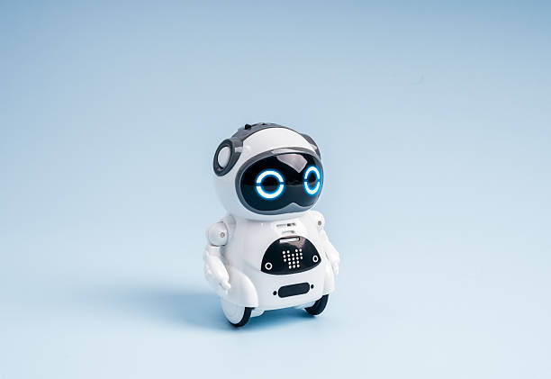 istock Cute small robot with glowing blue eyes on minimal background. Concept of AI technology, chatbot assistant, AI agent, machine learning, robotics innovation, artificial intelligence, and future tech. 2237969194