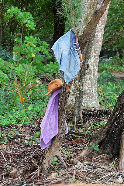 istock Denim shorts, brown hat and purple towel hanging from a tree at a beach 2237970469