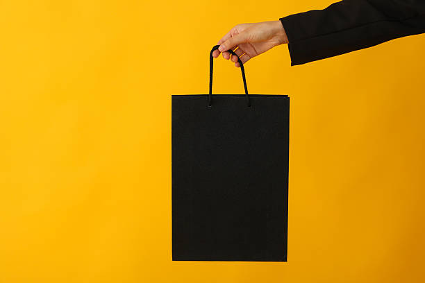 istock Paper shopping bag in hand on yellow background. 2237972775