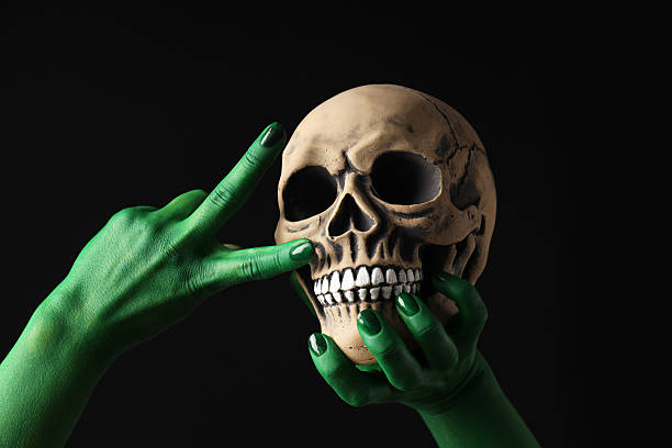 istock Green, painted hands show a peace gesture, next to a skull. 2237973892