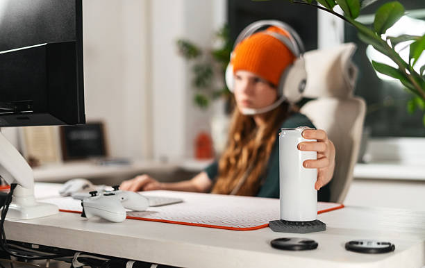 Gamer hand smoothly reaches for an energy drink while adjusting modern keyboard. Ergonomic desk mat provides wrist support, ensuring comfort for extended gaming and work sessions.
