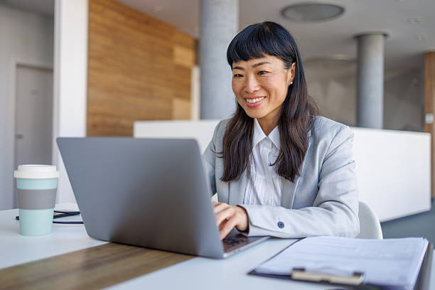 istock Asian businesswoman smiling while working on laptop in modern office 2237981180