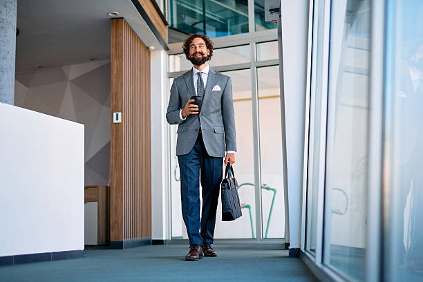istock Confident businessman walking in modern office holding coffee 2237981435