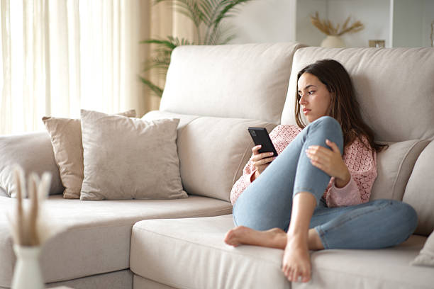 istock Serious woman checking mobile phone on a sofa at home 2237986781
