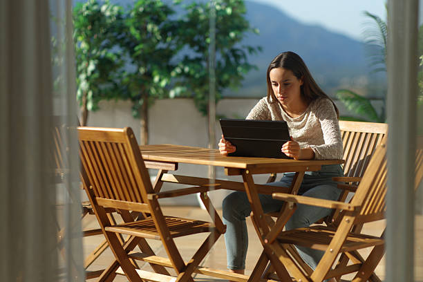 istock Woman in a terrace at home using tablet a sunny day 2237986829