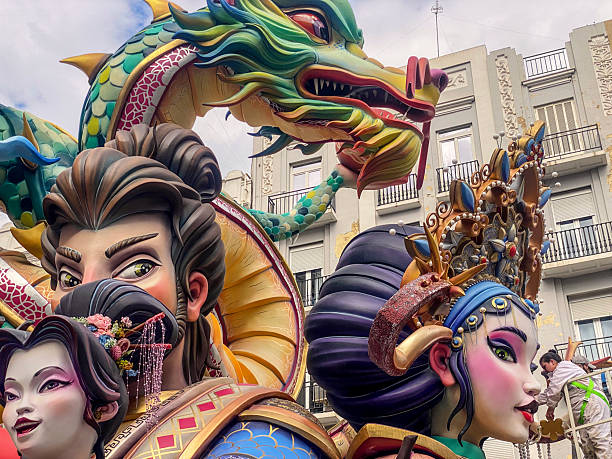 Valencia, Spain - March 15, 2025: Low angle view of a Fallero master giving the final touches to ninots placed in the city downtown. These are huge dolls that are built specifically to be burnt during the last night of Las Fallas annual event, exclusive to the Valencian Community