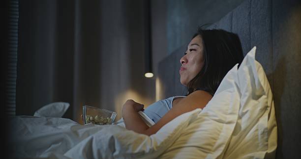 istock Before Sleeping, Girl in Bed Snacks in Front of TV 2237990688