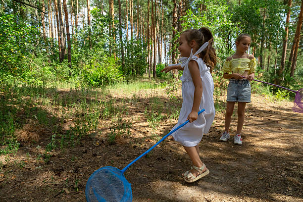 Street orienteering in a sunny pine forest. An athlete runs past a prism control point.