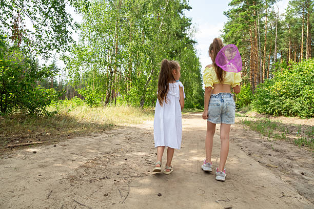 Two little girls catching insects with nets in forest