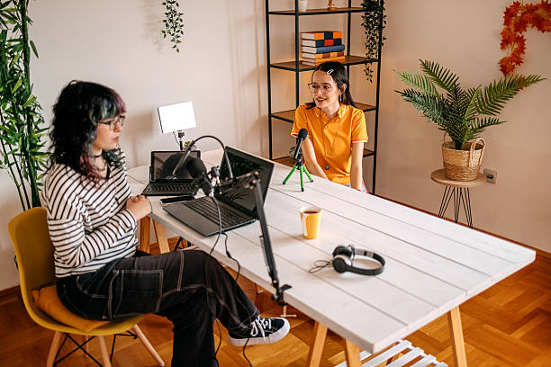 istock Female friends talking while filming podcast at home 2237998376
