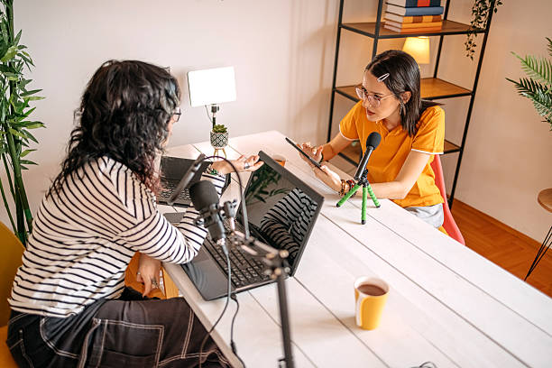 istock Female friends having discussion while filming podcast at home 2237998564