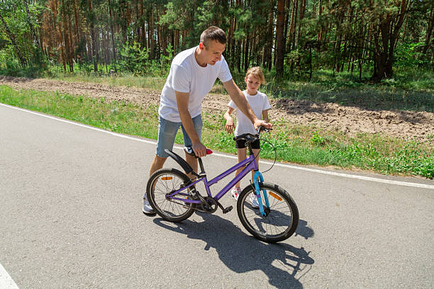 istock Father teaching his daughter how to ride a bicycle in forest 2237999045