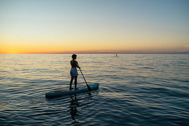 istock Young woman on SUP paddle board in sunset 2238000552