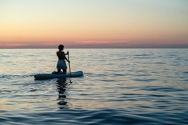 istock Young woman on SUP paddle board in sunset 2238000560