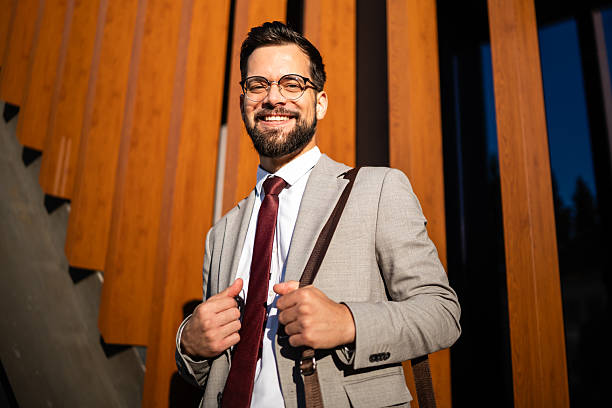 istock Smiling businessman adjusting his jacket in front of modern building 2238003684