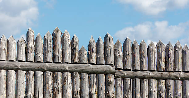 A wooden fence with many wooden posts. The fence is made of wood and is brown in color