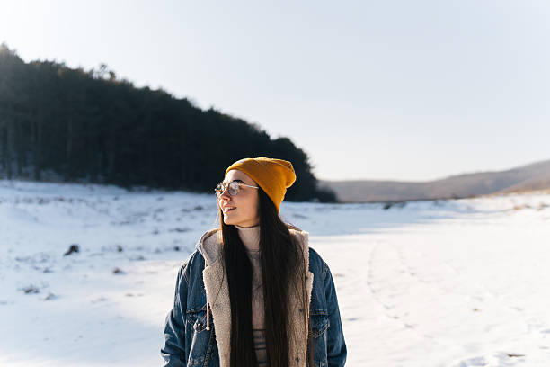 Photo of a young woman enjoys the nature covered in snow on a cold but sunny day