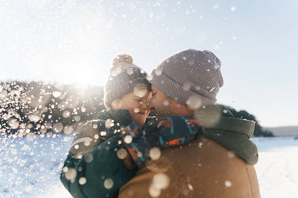 Photo of a father and son, having precious moments on a snowy day they are spending outdoors, in nature