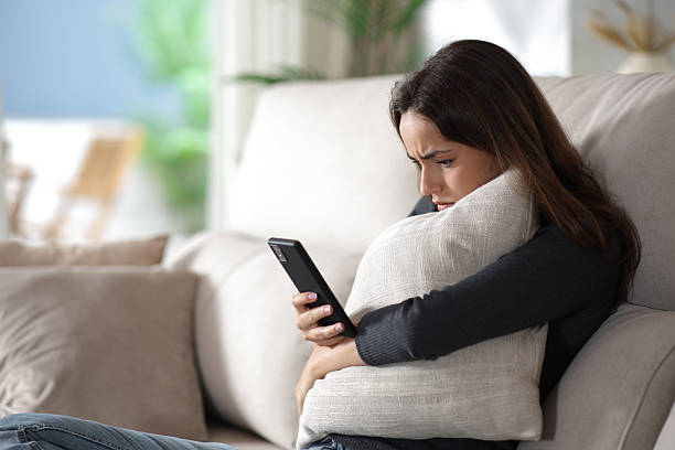 istock Sad woman checking phone hugging pillow at home 2238007174