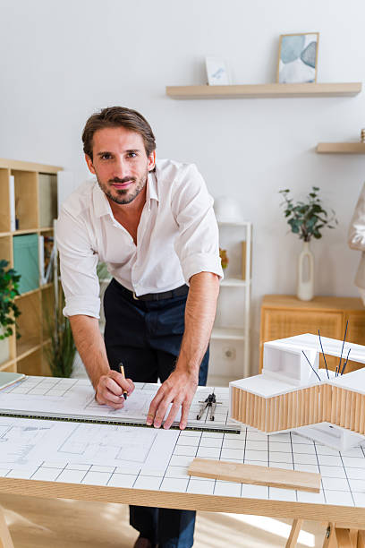 istock Male architect smiling while drawing blueprint in office 2238007347
