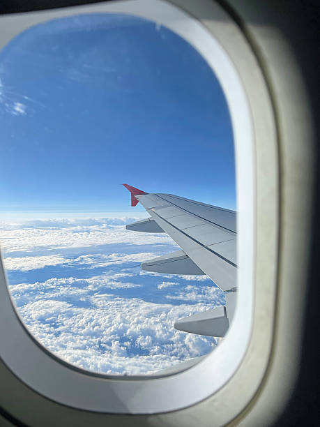 istock View from the airplane window. Beautiful cloudscape with blue sky. Wonderful panorama above white clouds as seen through window of an plane. Traveling by air concept. Selective focus. 2238007982