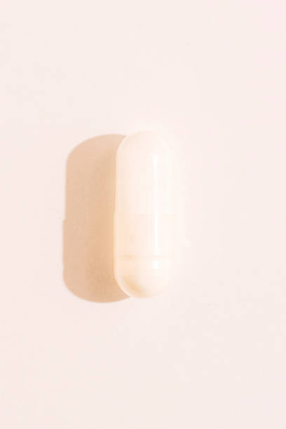 istock Single white capsule macro with strong side shadow on pastel background healthcare supplement concept 2238008675