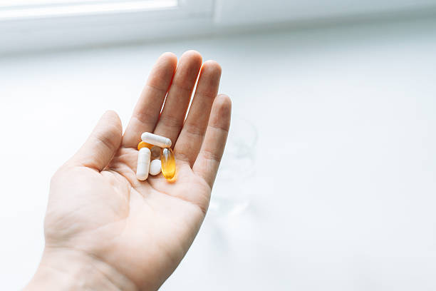 istock Hand holding assorted vitamins and capsules by a bright window on white background 2238008756