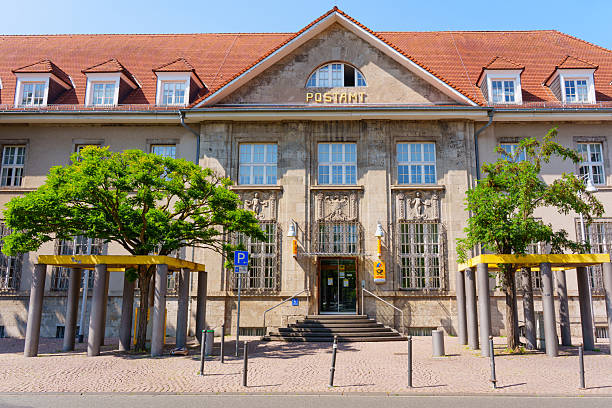 Darmstadt, Germany - June 19, 2025: Front view of a historic post office building in Darmstadt, Germany featuring elegant architecture, large windows, and surrounding greenery under bright sunlight.
